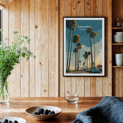 Oxnard California Wall Art Print | Palm Tree Lined Coastal Travel Poster displayed in a cozy interior with wooden accents.