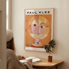 Paul Klee Senecio Head of Man Abstract Portrait Poster Art Print displayed on a wall with a person studying nearby.