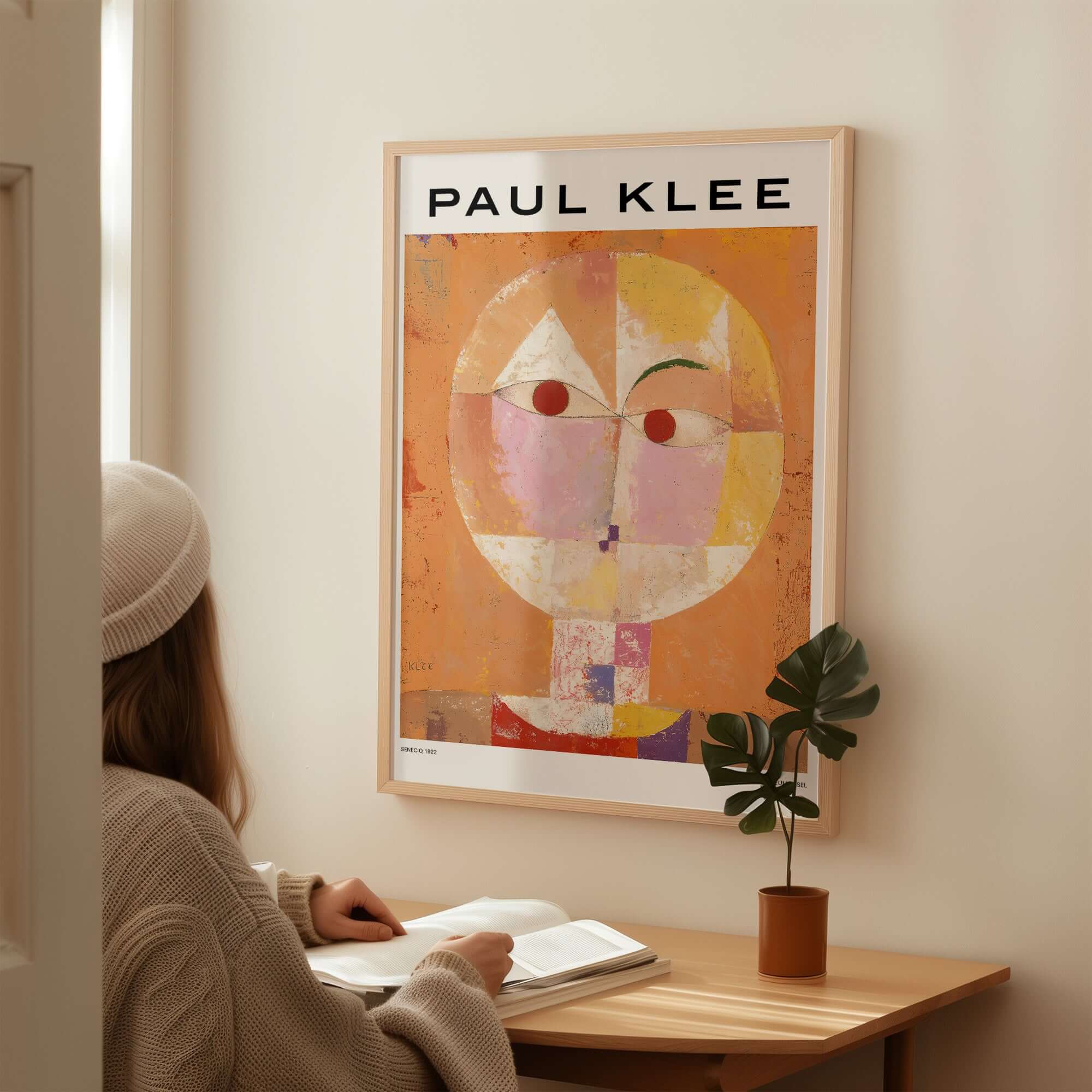 Paul Klee Senecio Head of Man Abstract Portrait Poster Art Print displayed on a wall with a person studying nearby.