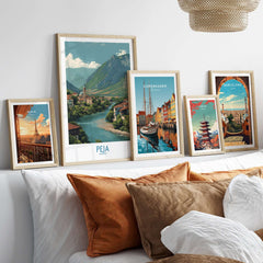 Peja Kosovo River Valley Art Print | Mountain Town Scenery Poster displayed among various city art prints on a cozy couch.