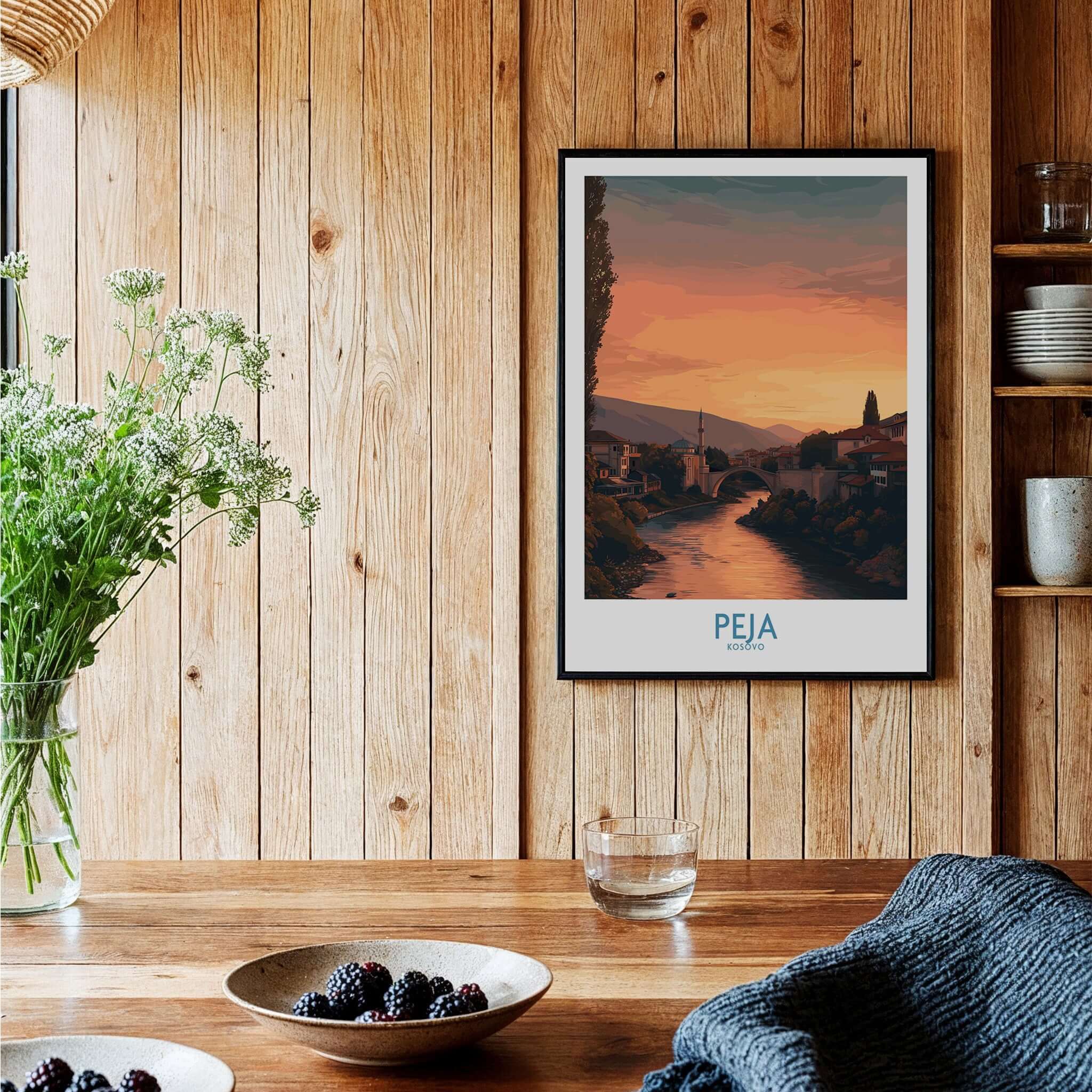 Peja Kosovo Sunset River Bridge Art Print | Mosque and Mountains Poster framed on a wooden wall with flowers and bowls.