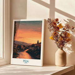 Peja Kosovo Sunset River Bridge Art Print | Mosque and Mountains Poster displayed beside a vase with flowers.