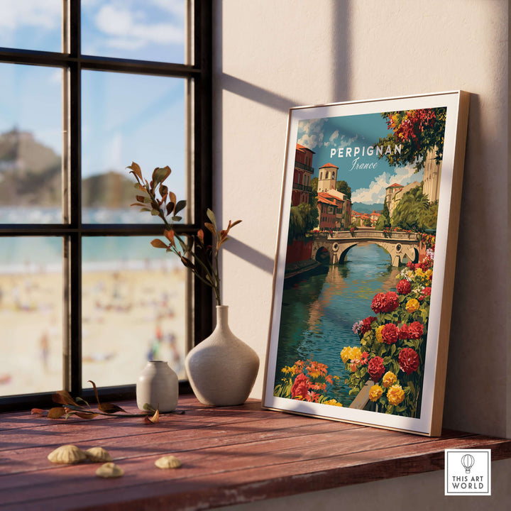 Perpignan cityscape art print by the River Le Basse, framed on a wooden table by a sunny window.