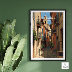 Perpignan Poster - French Village Art Print - Wall Decor showcasing vibrant street scene in a quaint village framed on a green wall.