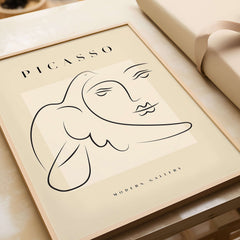 Picasso Line Art Face Dove Minimalist Modern Gallery Poster Print displayed on a wooden table with elegant wrapping.