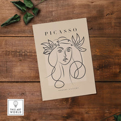 Picasso Line Art Woman Leaf Crown Modern Gallery Wall Art Poster displayed on a wooden surface with foliage.