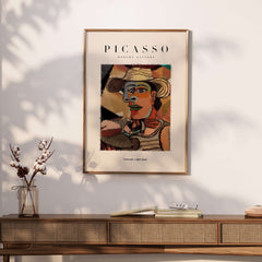 Picasso Man Straw Hat Abstract Portrait Art Print Cubist Poster Artwork Collection framed on a wall above a wooden table.