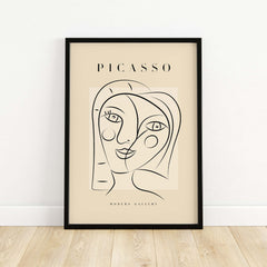 Picasso Smiling Double Face Abstract Portrait Line Art Modern Gallery Poster Print in a black frame on a beige background.