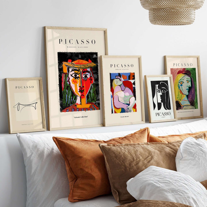 Collection of framed Picasso posters featuring colorful abstract portraits on a stylish couch with decorative pillows.