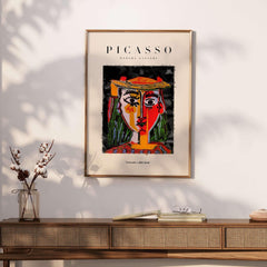 Picasso Woman in Hat Red Yellow Face Portrait Poster Colorful Abstract Artwork Print on a wall above a wooden console.