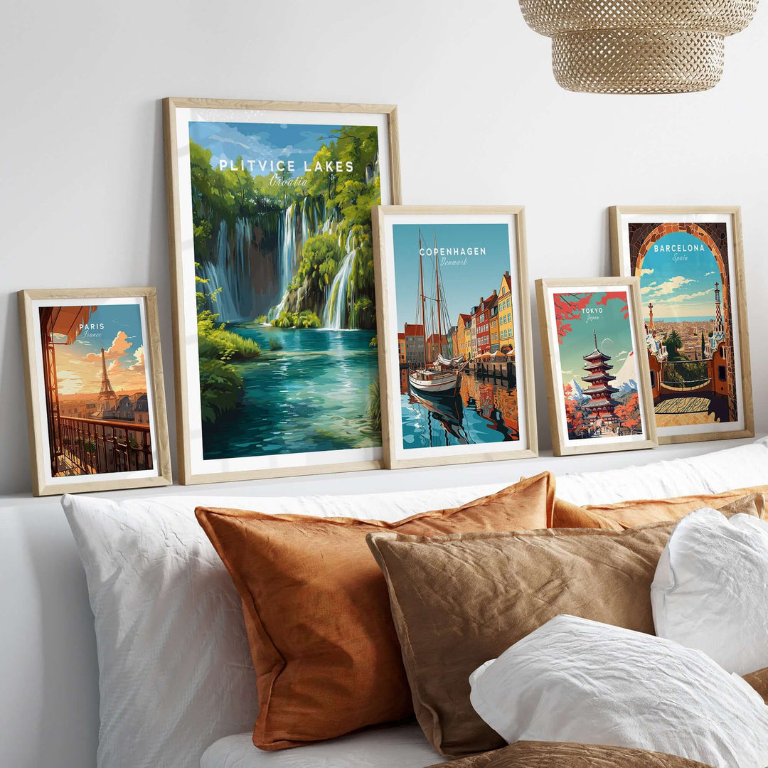 Framed art prints of Plitvice Lakes, Copenhagen, and Barcelona displayed on a couch, showcasing scenic European landscapes.