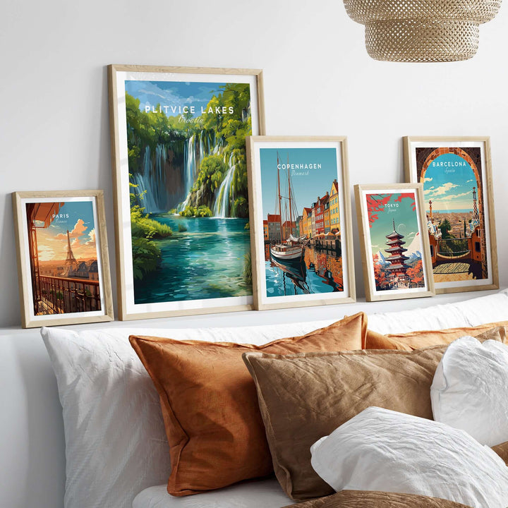 Framed art prints of Plitvice Lakes, Copenhagen, and Barcelona displayed on a couch, showcasing scenic European landscapes.