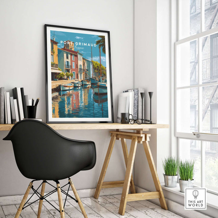 Port Grimaud village art print framed on wall above a stylish desk, featuring colorful coastal reflections.