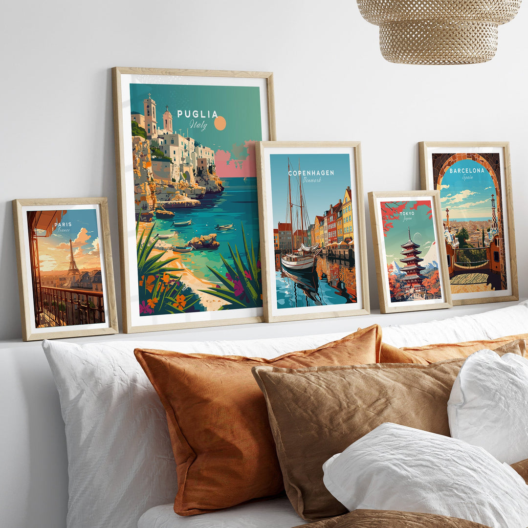 Collection of framed travel posters including Puglia, Copenhagen, and Barcelona, displayed on a wall above a cozy couch.