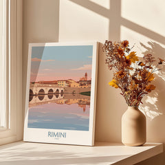 Rimini Italy Poster | Panoramic River Cityscape Scene Canvas Print displayed beside a vase with flowers and sunlight.