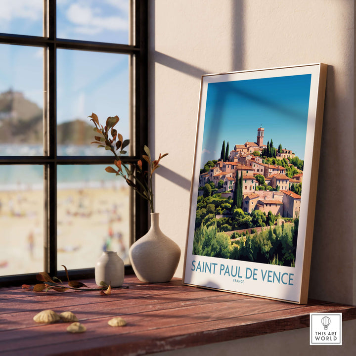 Saint Paul de Vence travel poster featuring a scenic view, framed on a table near a sunny window.