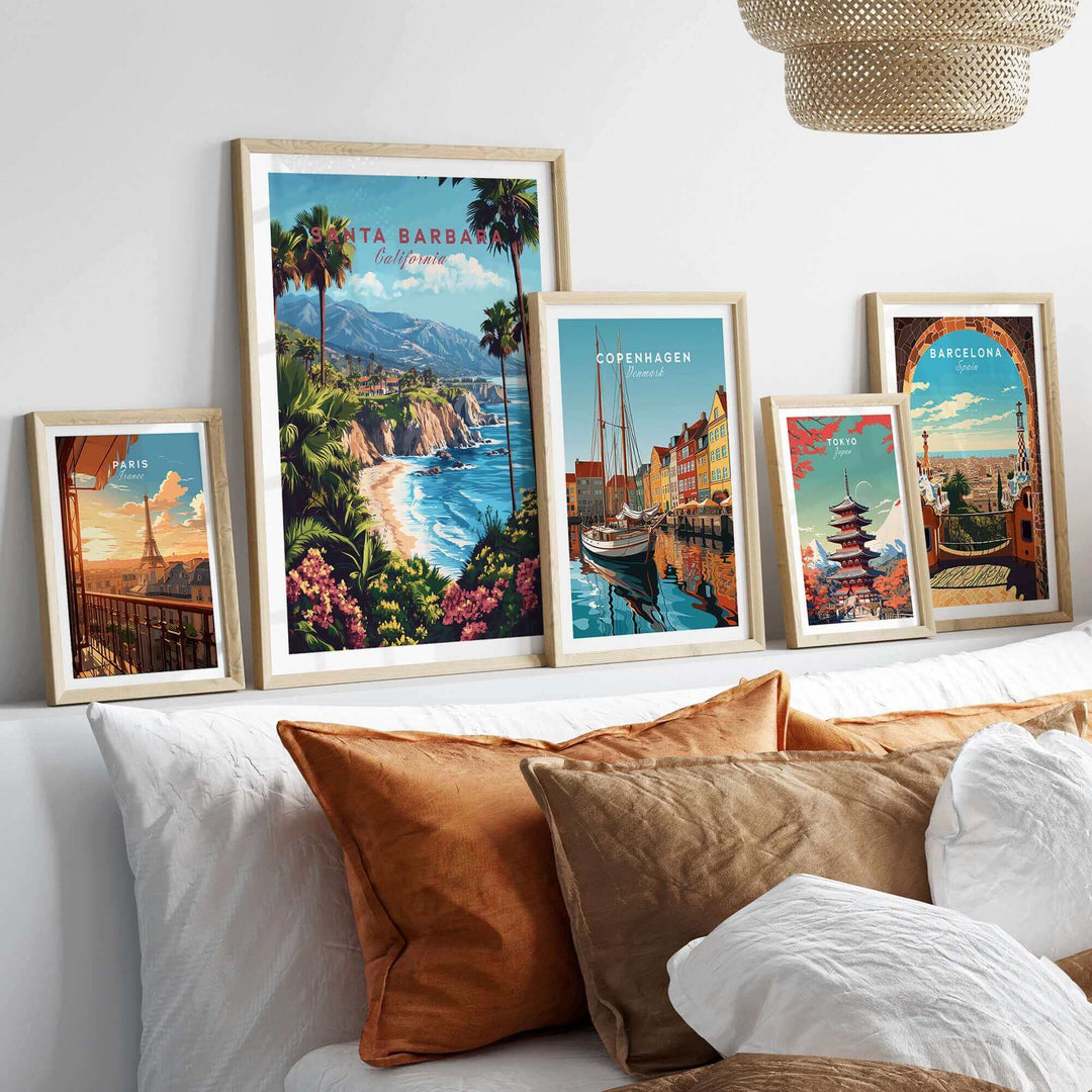 Framed Santa Barbara travel print displayed with various international city posters, showcasing vibrant ski poster art on a sofa.