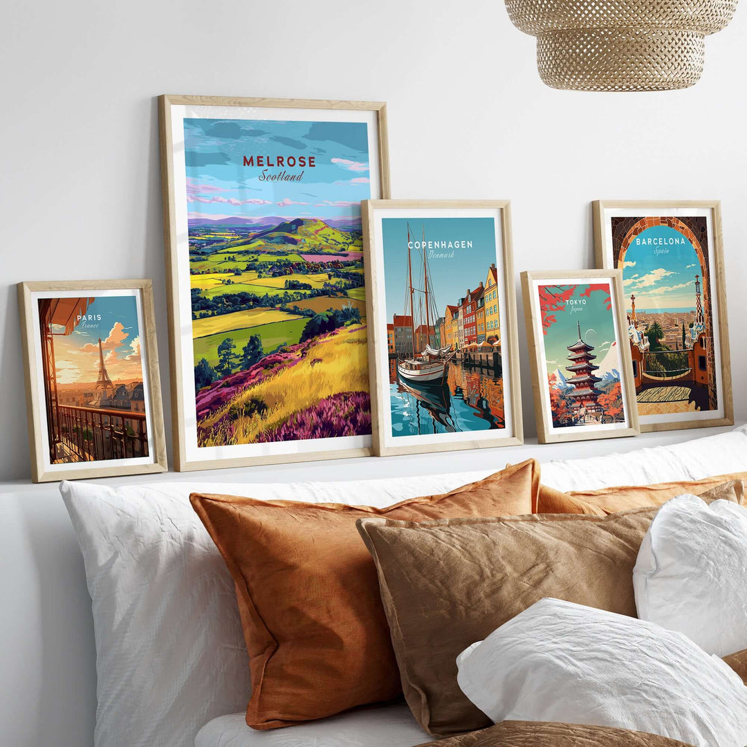 Collection of travel prints featuring Melrose, Copenhagen, and Barcelona in decorative frames on a stylish sofa.