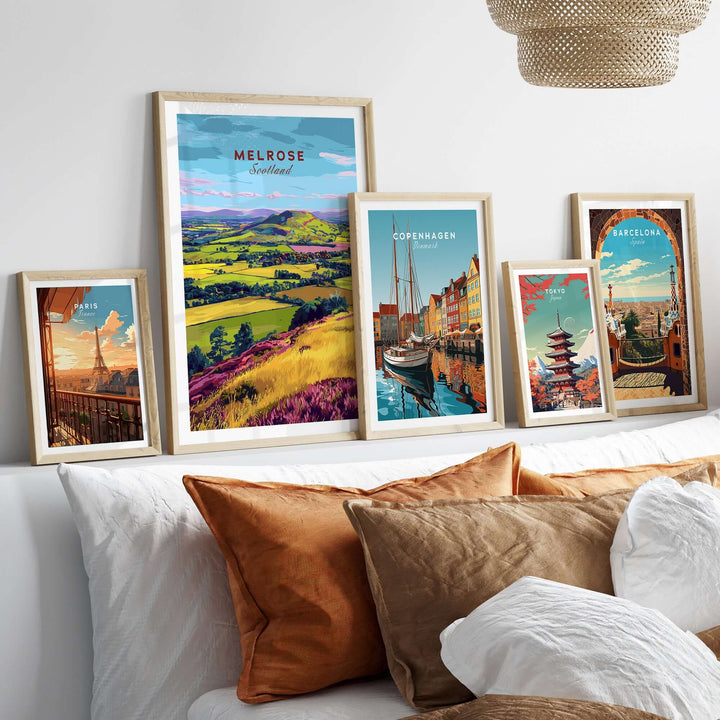 Collection of travel prints featuring Melrose, Copenhagen, and Barcelona in decorative frames on a stylish sofa.