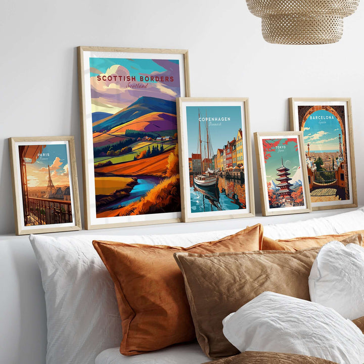 Scottish Borders Valley travel print and other city posters displayed on a stylish sofa, showcasing vibrant landscapes.
