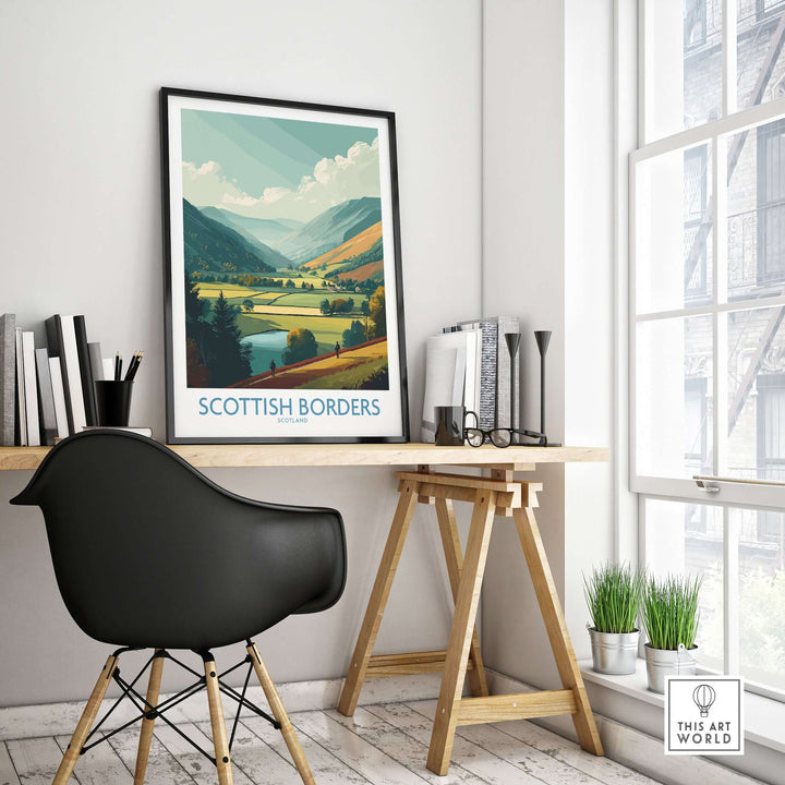 Scottish Borders travel poster displayed in a modern workspace, highlighting a picturesque valley and mountains.
