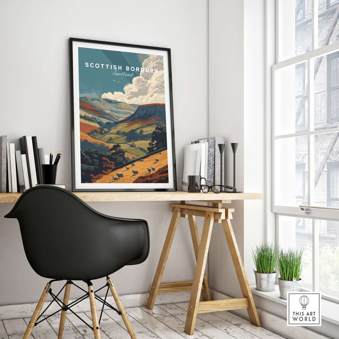 Scottish Borders travel poster with sheep grazing in a valley, displayed in a modern interior workspace.