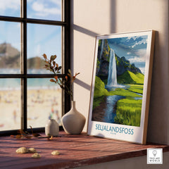 Seljalandsfoss Iceland Waterfall Art Print displayed on a table by a window overlooking a beach.