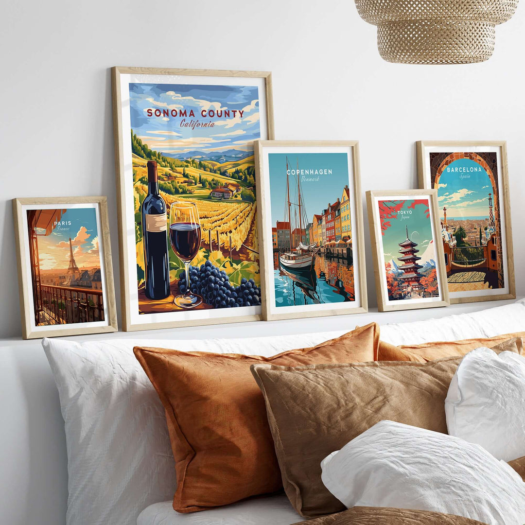 Framed Sonoma County wine poster with travel prints of Copenhagen and Barcelona above a cozy sofa with decorative cushions.