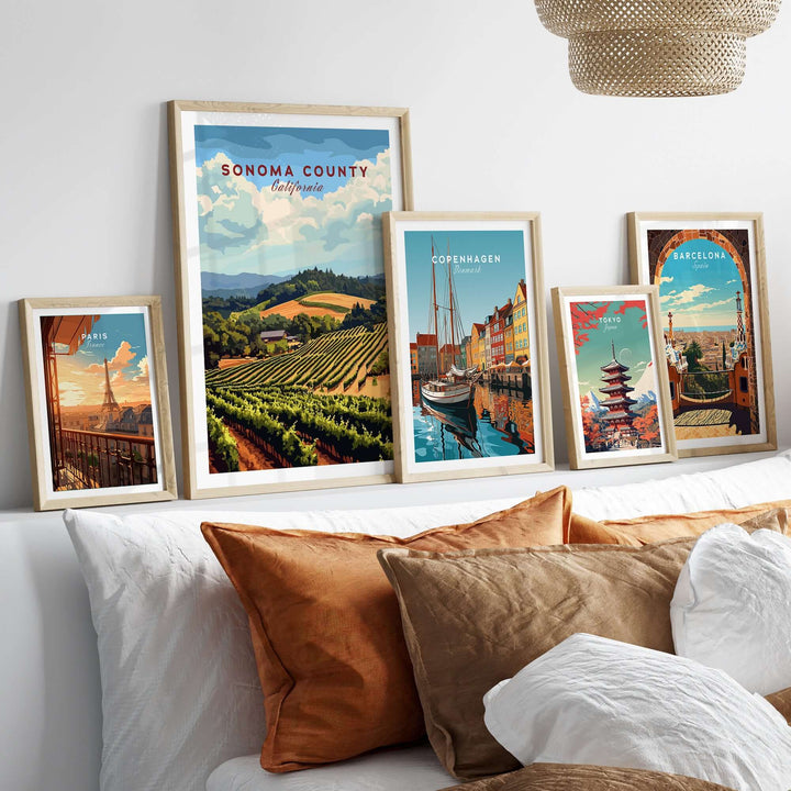 Sonoma County vineyard art print and travel posters framed on a wall beside cozy throw pillows.