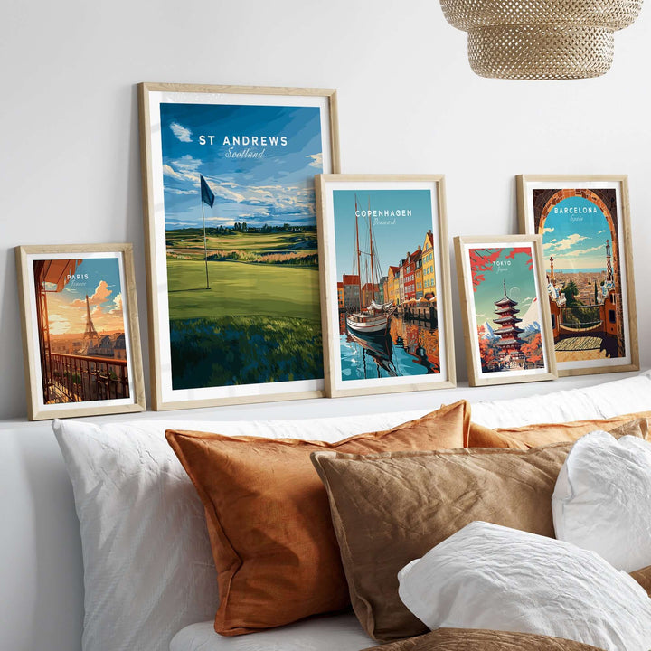 St Andrews poster among framed travel prints on a stylish bed, showcasing iconic landscapes and culture.