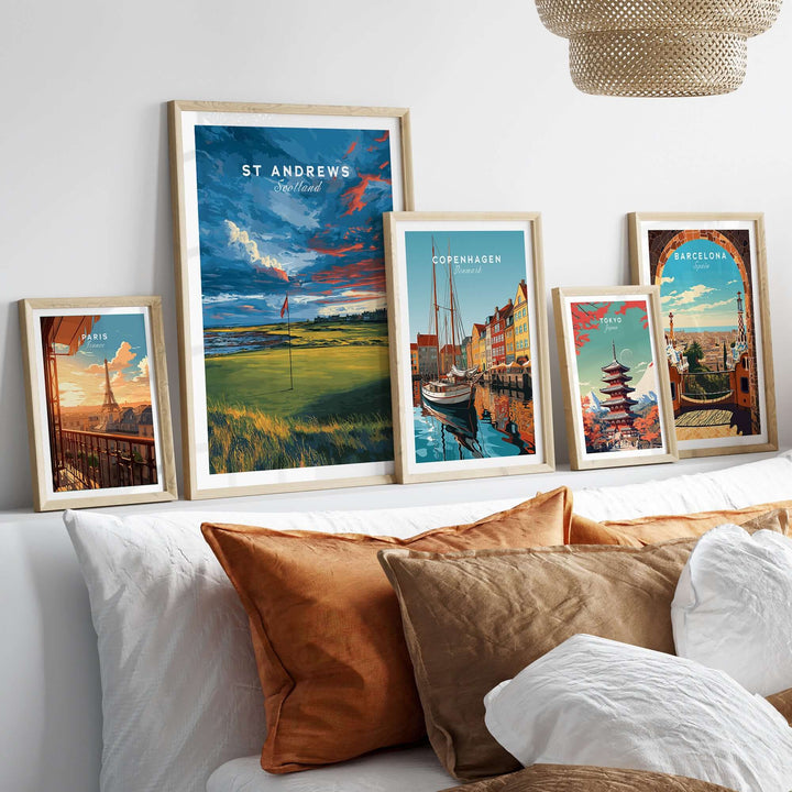 Framed St Andrews poster among cityscape artwork on a cozy couch, showcasing iconic destinations.