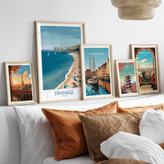 Swanage Dorset Poster | White Cliffs & Coastal Sailboat Scene Canvas Print displayed among other travel posters on a stylish couch.