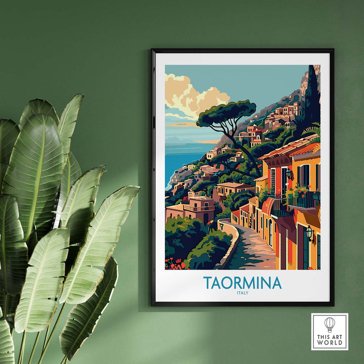 Taormina Travel Print displayed on green wall with large leaves. Vibrant depiction of Italy's coastline, perfect for home decor.