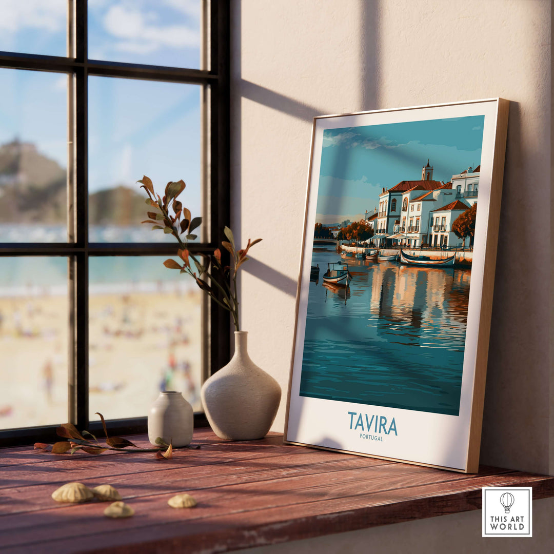 Framed Tavira Algarve poster by a window, showcasing picturesque coastal scenery and tranquil waters.