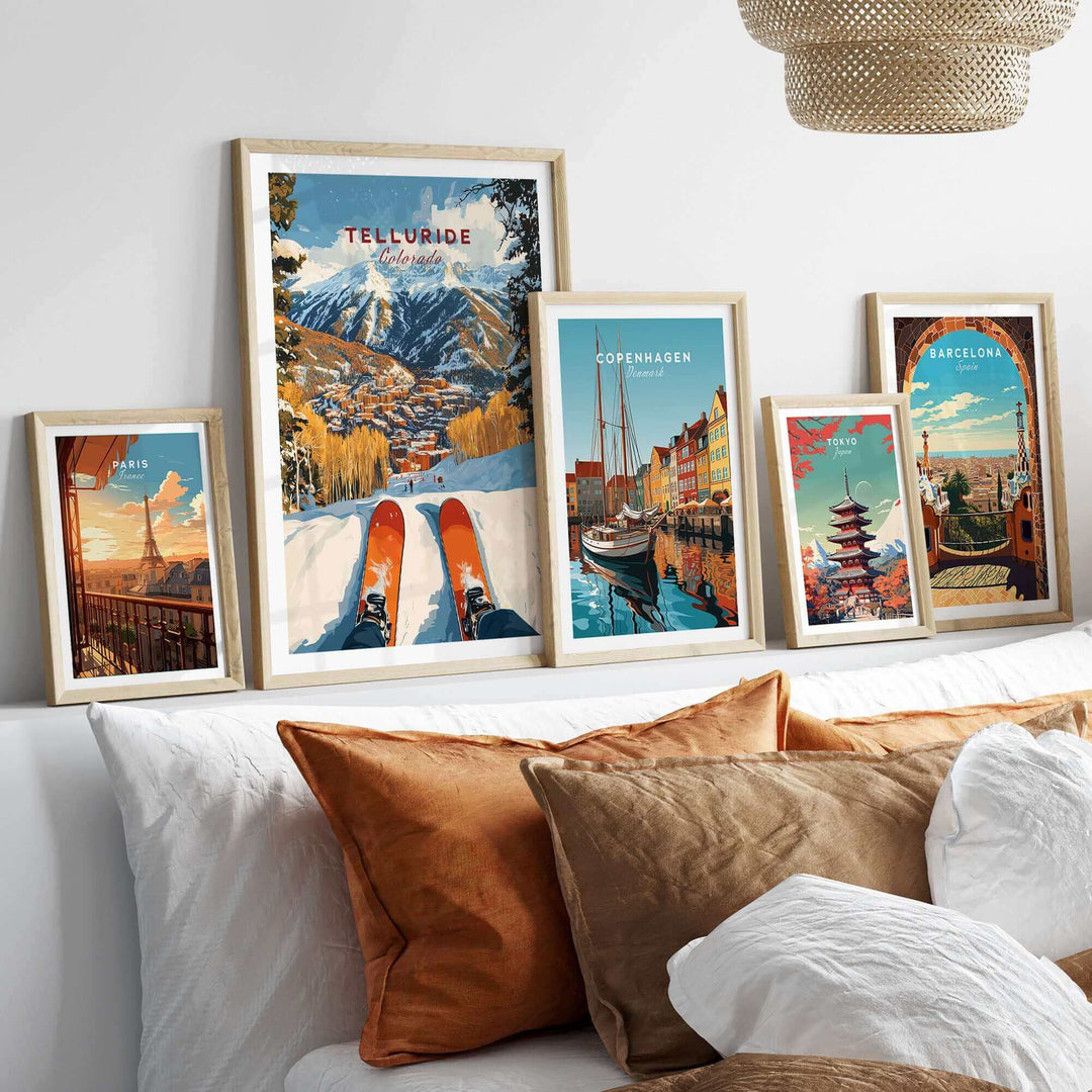 Collection of framed travel posters including Telluride Ski Poster displayed on a shelf above a cozy bed setting.