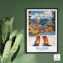 Telluride wall art ski poster featuring vibrant ski scene in Colorado mountains, framed on a green wall with plant.