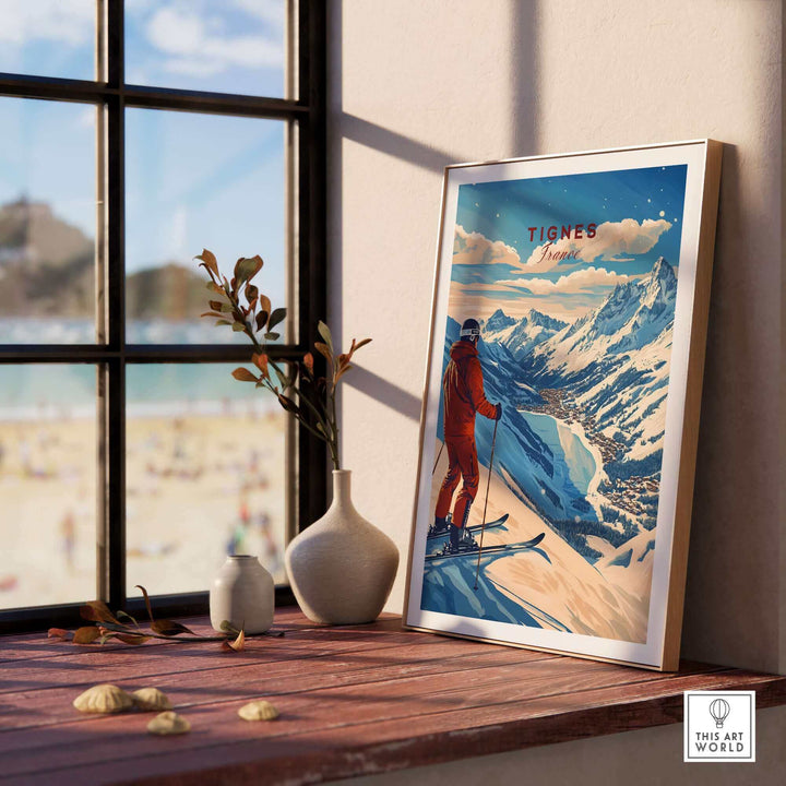 Tignes Print France Ski Poster displayed on a windowsill, featuring snowy mountains and a skier in a red outfit.