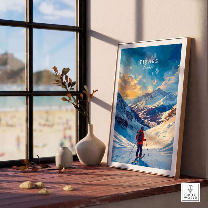 Framed Tignes Ski Poster in sunlight on wooden shelf with beach view background, featuring skier in snowy mountain landscape.