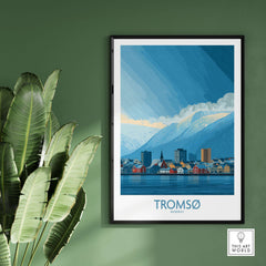 Tromsø Norway Art Print | Snowy Mountain City Poster framed on a green wall with a plant, showcasing vibrant colors.