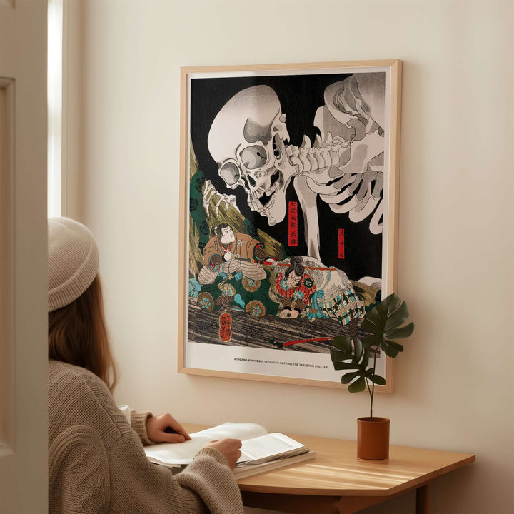 Person reading near Utagawa Kuniyoshi's Skeleton Spectre Ukiyo-e wall art print showcasing dramatic Japanese folklore.