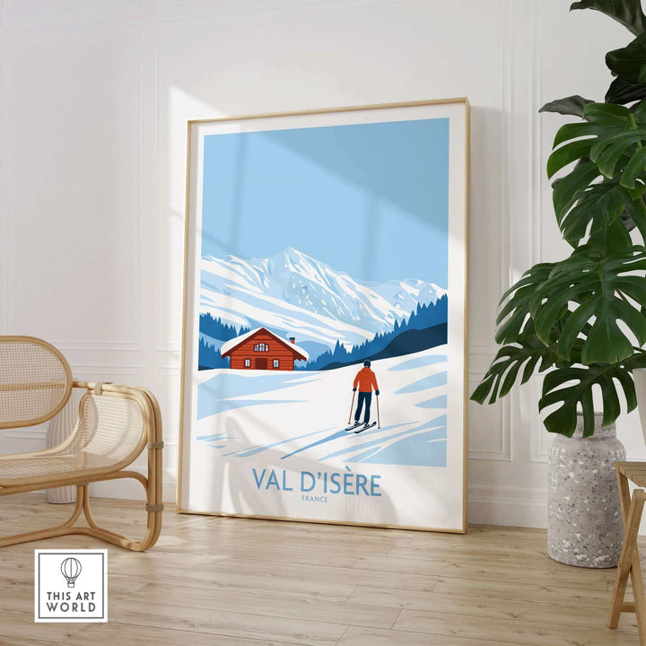 Val-d'Isère France print featuring skier in snowy mountains, displayed in stylish room with wicker chair and green plant.