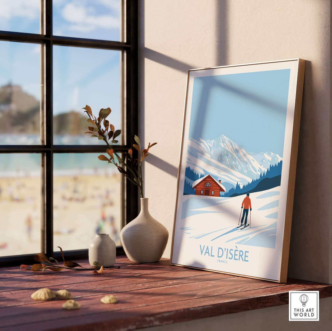 Stylish Val-d'Isère France print displayed near a window, featuring a skier, snowy mountains, and a cozy cabin.