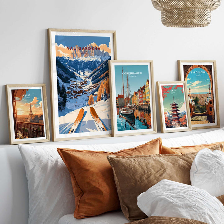 Val Gardena travel poster displayed among framed travel art prints on a stylish bed with decorative pillows.