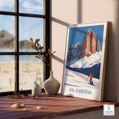 Val Gardena wall art ski poster displayed on a sunny windowsill with a scenic alpine landscape and skier in the artwork.
