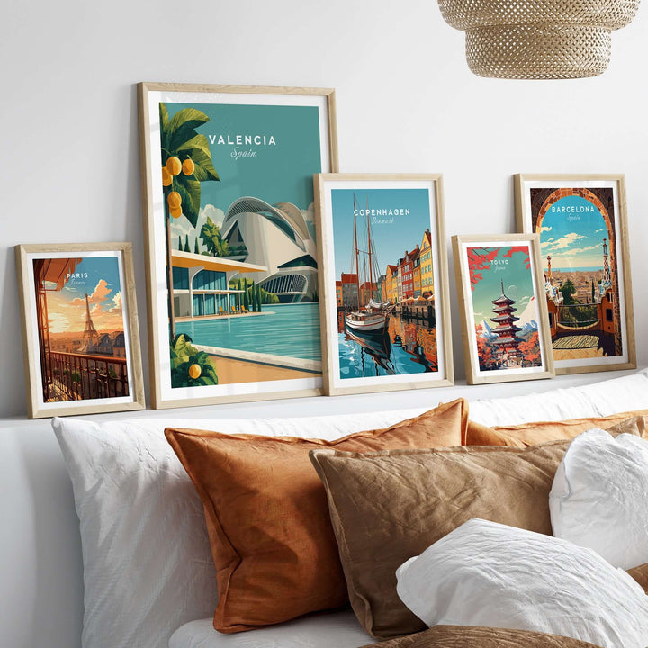 Framed prints of Valencia, Copenhagen, and Barcelona posters on a stylish sofa, showcasing vibrant cityscapes.
