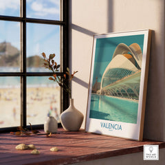 Valencia Travel Poster Spain displayed on a wooden table near a window with a beach view and modern architecture.
