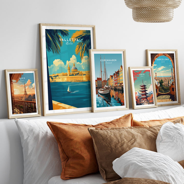 Art prints of Valletta, Copenhagen, Barcelona, and more displayed in frames on a shelf above a sofa with colorful cushions.