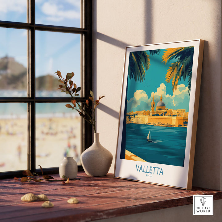 Valletta Print poster displayed on a windowsill with a beach view, capturing Malta's city skyline and architecture. Perfect for home decor.