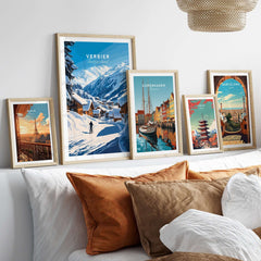 Scenic display of framed travel prints including Verbier, Switzerland, set against a cozy home interior with decorative cushions.