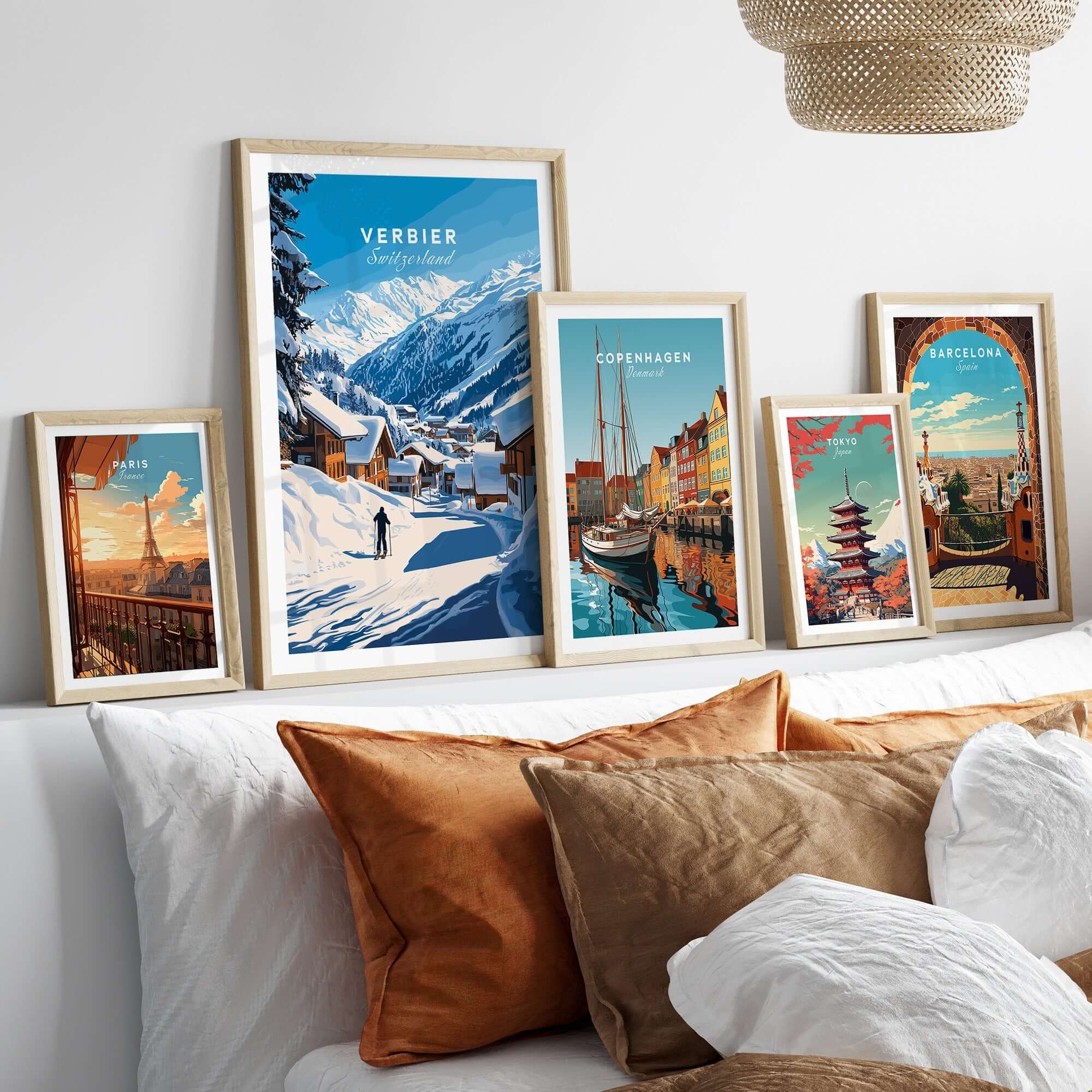 Scenic display of framed travel prints including Verbier, Switzerland, set against a cozy home interior with decorative cushions.